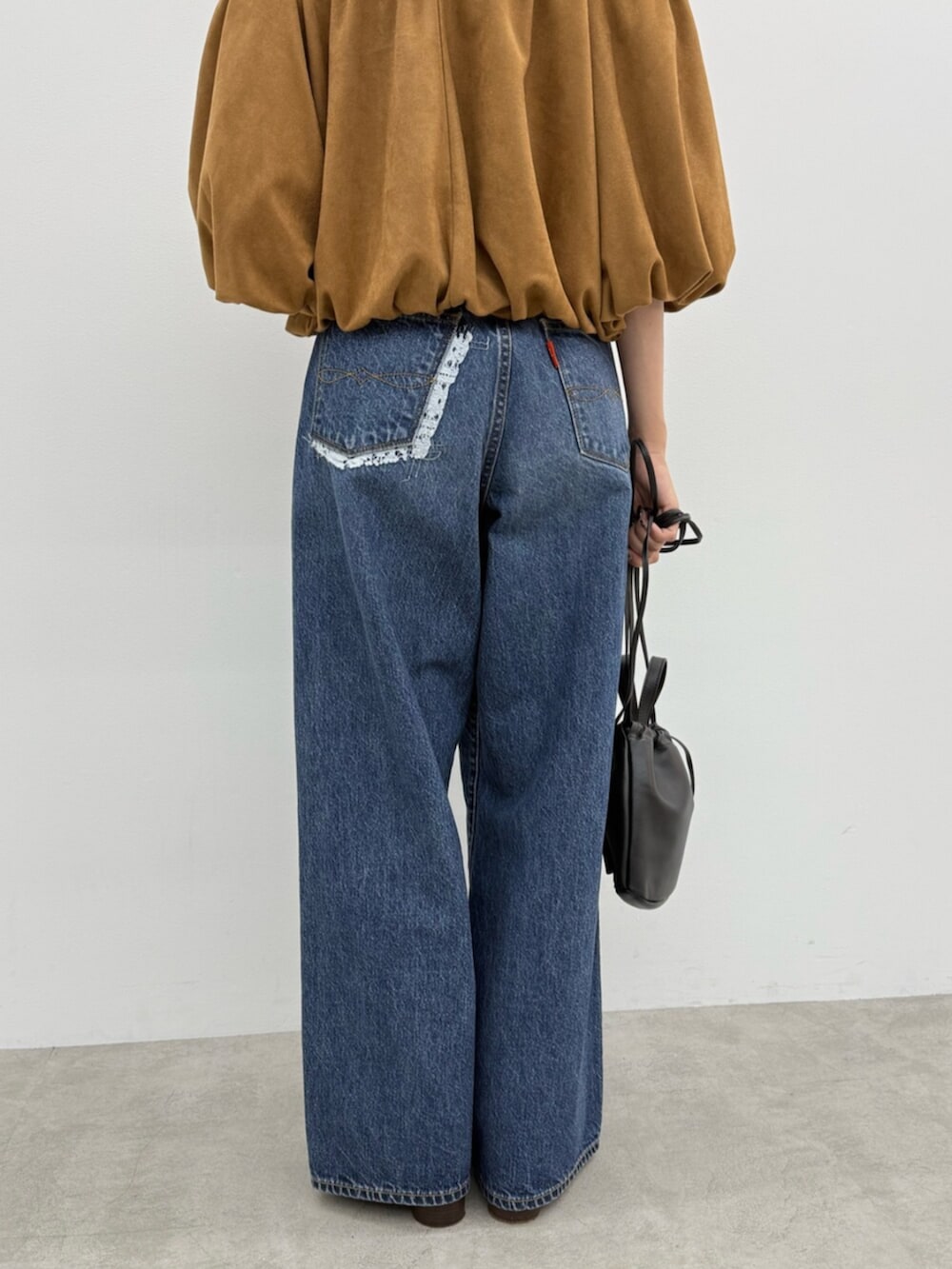 ブラウン系のブーツ、ブラック系のショルダーバッグ、ブルー系のデニムパンツを着用したレディースの秋コーディネートの6枚目の写真