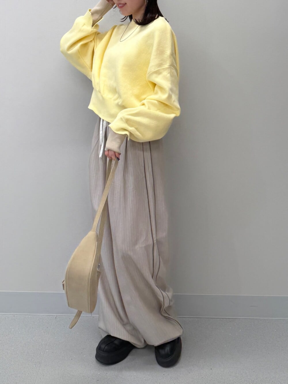 ベージュ系のハンドバッグ、イエロー系のニット/セーター、ブラック系のブーツを着用したレディースの冬コーディネートの3枚目の写真