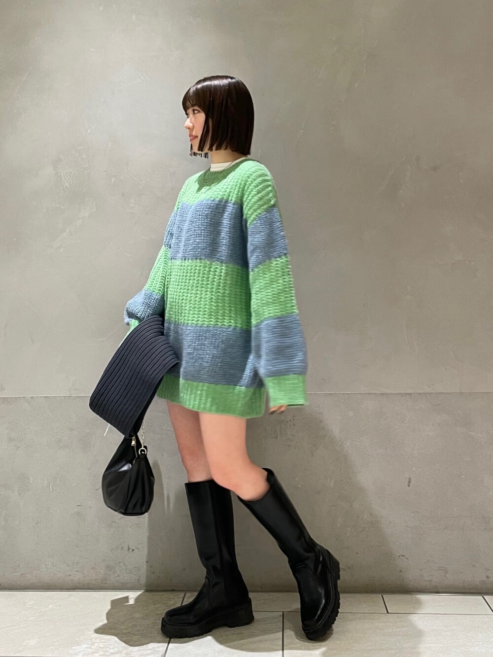 グリーン系のニット/セーター、ホワイト系のTシャツ/カットソー、グレー系のマフラーを着用したレディースの冬コーディネートの2枚目の写真