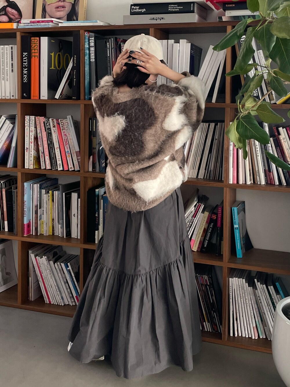 グレー系のスカート、ベージュ系のニット/セーター、ホワイト系のキャップを着用したレディースの秋コーディネートの5枚目の写真