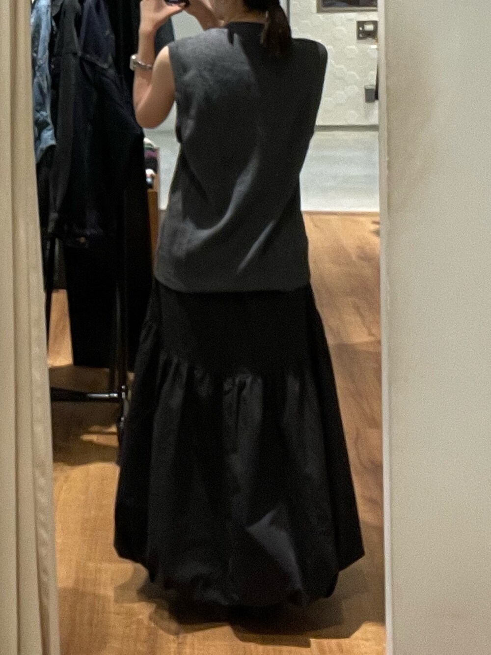 ブラック系のスカート、ブラック系のブーツ、グレー系のベストを着用したレディースの秋コーディネートの5枚目の写真