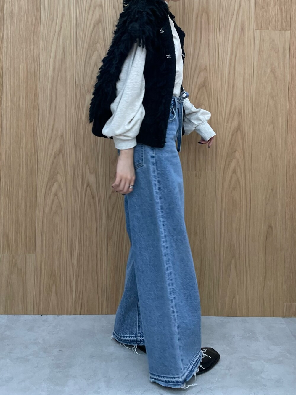 ブルー系のデニムパンツ、ブラック系のブーツ、グレー系のスウェットを着用したレディースの秋コーディネートの4枚目の写真