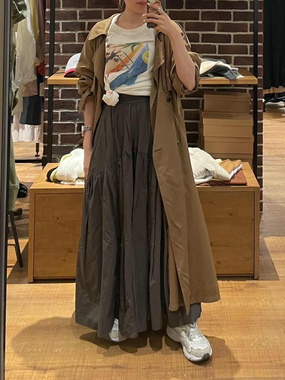 イエロー系のトレンチコート、グレー系のスカート、ホワイト系のTシャツ/カットソーを着用したレディースの春コーディネートの5枚目の写真