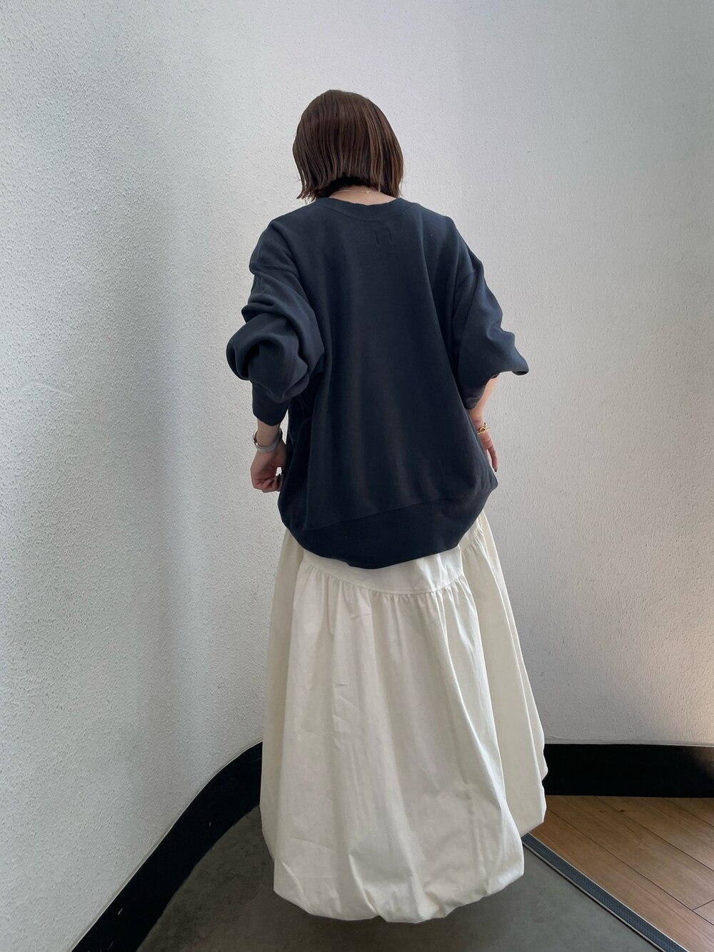 グレー系のスウェット、ホワイト系のスカート、グリーン系のスニーカーを着用したレディースの夏コーディネートの4枚目の写真