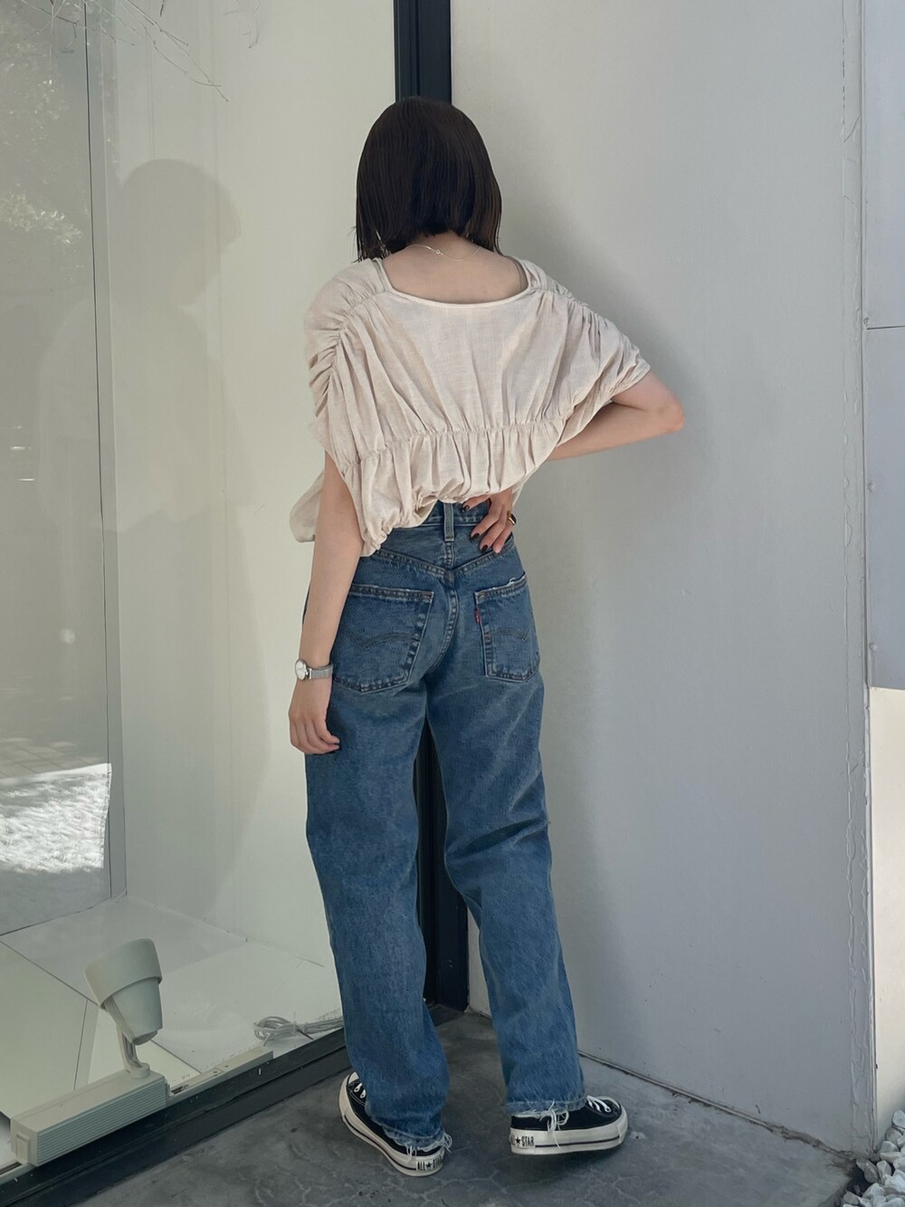 ホワイト系のシャツ/ブラウス、ブラック系のスニーカー、ブルー系のデニムパンツを着用したレディースの夏コーディネートの4枚目の写真