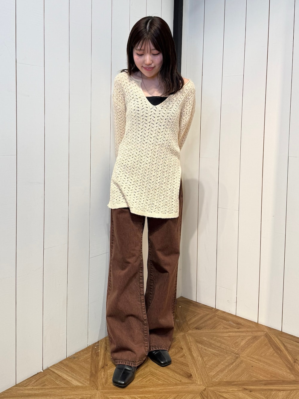 ブラウン系のデニムパンツ、ブラック系のサンダル、ベージュ系のニット/セーターを着用したレディースの春コーディネートの2枚目の写真