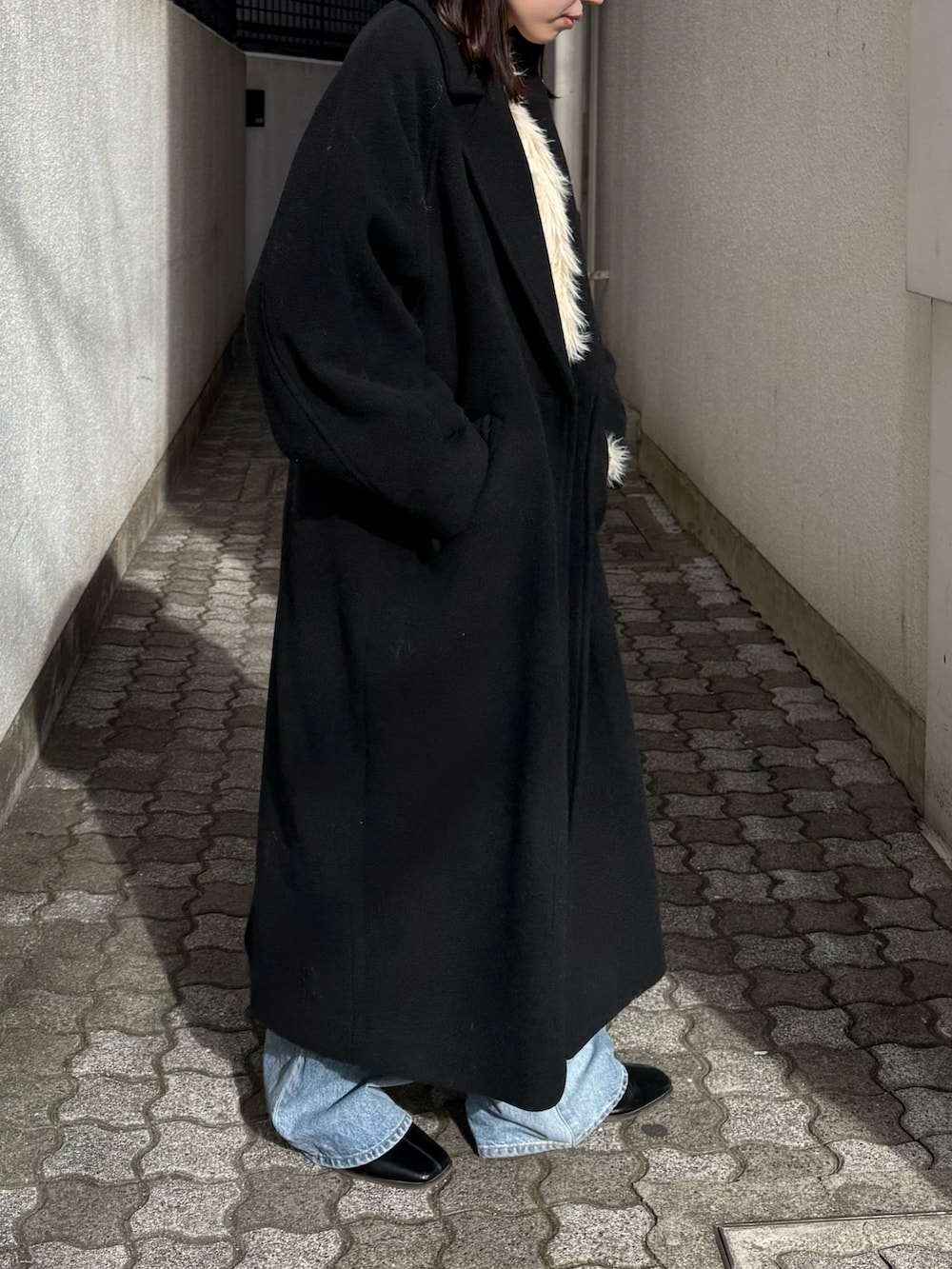 ブルー系のデニムパンツ、ブラック系のブーツ、ブラック系のチェスターコートを着用したレディースの冬コーディネートの5枚目の写真