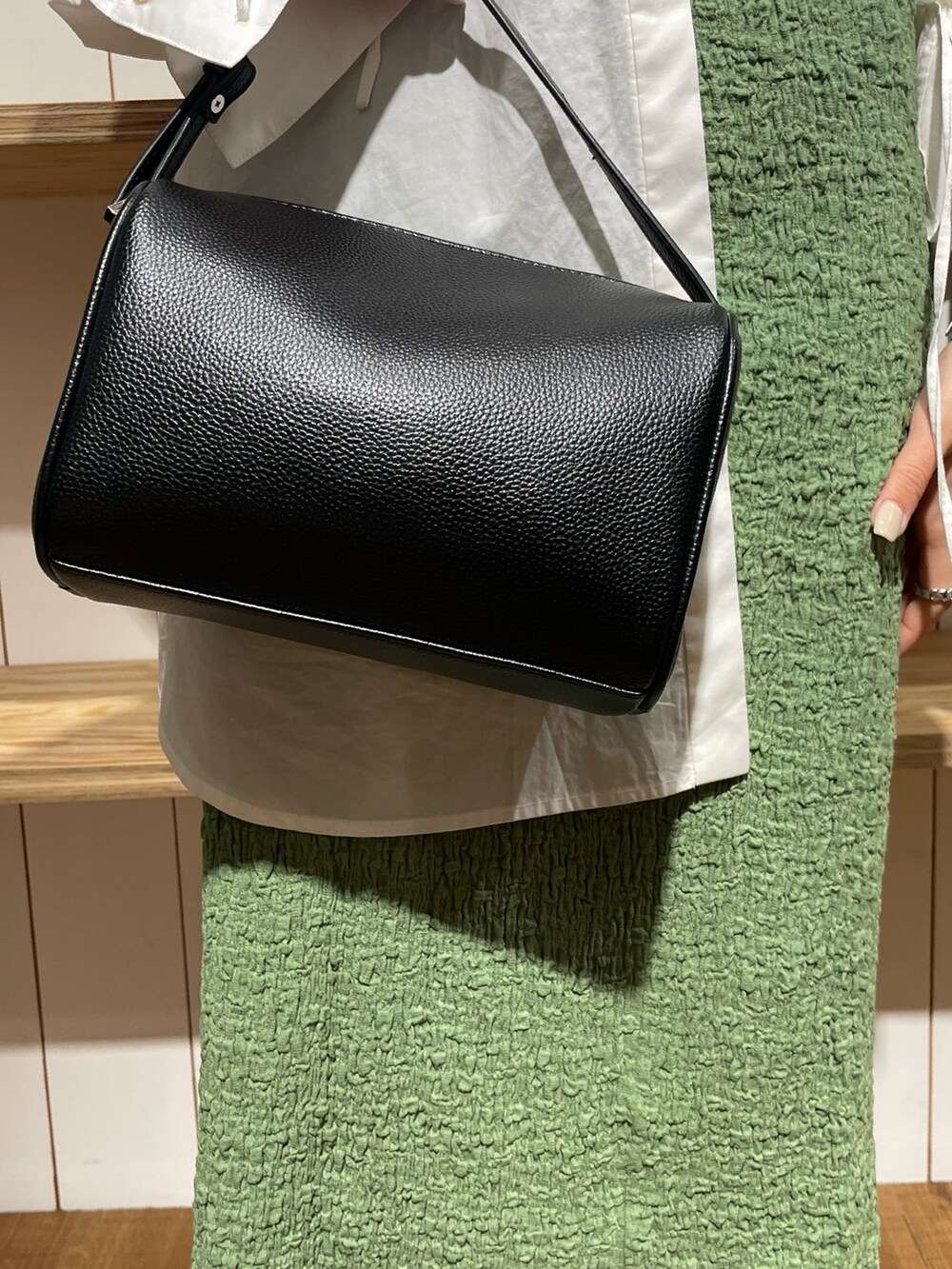 ブラック系のハンドバッグ、ブラック系のブーツ、ホワイト系のシャツ/ブラウスを着用したレディースの冬コーディネートの6枚目の写真