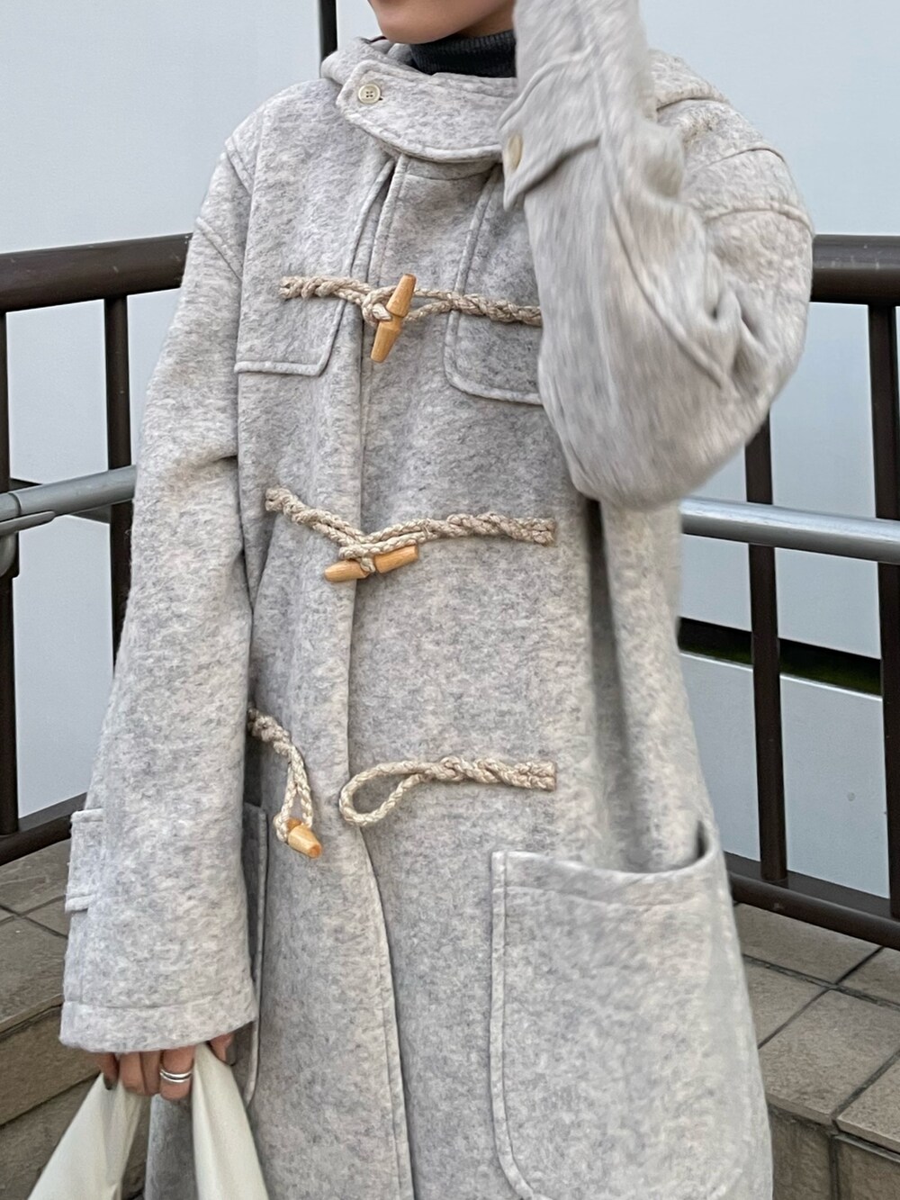 ピンク系のカーゴパンツ、ホワイト系のハンドバッグ、ホワイト系のダッフルコートを着用したレディースの冬コーディネートの5枚目の写真