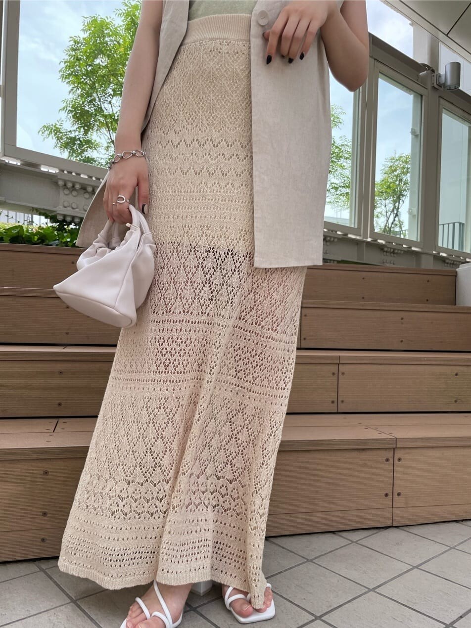 ベージュ系のスカート、ピンク系のハンドバッグ、グリーン系のタンクトップを着用したレディースの夏コーディネートの3枚目の写真