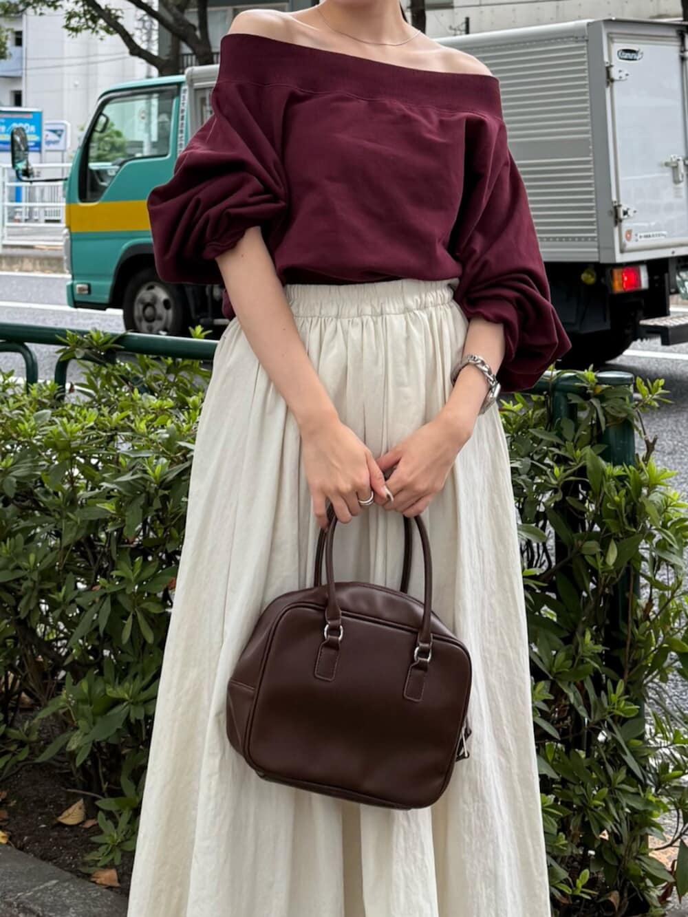 ブラウン系のハンドバッグ、ホワイト系のスカート、レッド系のスウェットを着用したレディースの秋コーディネートの4枚目の写真