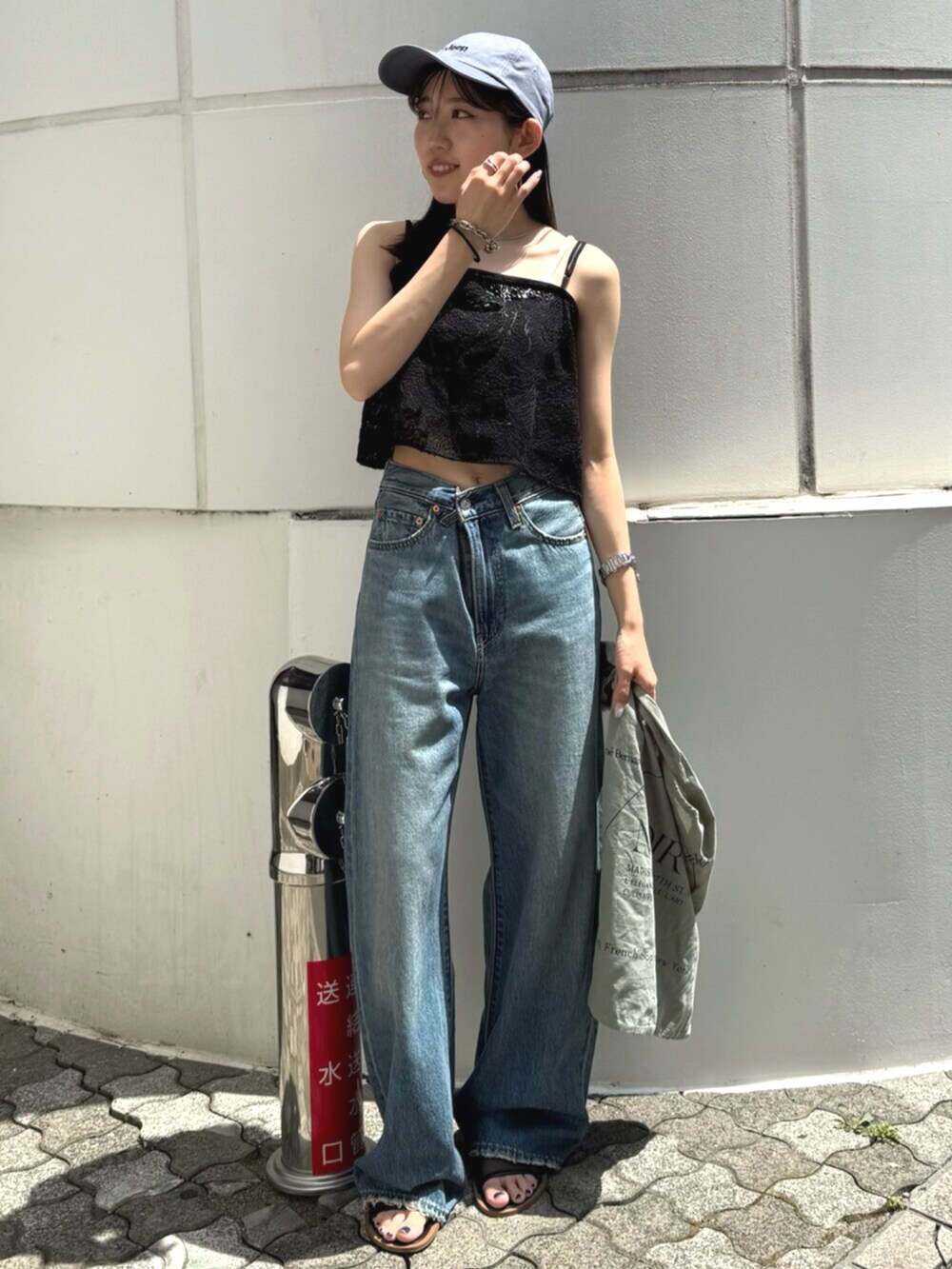 ブラック系のサンダル、グリーン系のトートバッグ、ブルー系のデニムパンツを着用したレディースの夏コーディネートの5枚目の写真