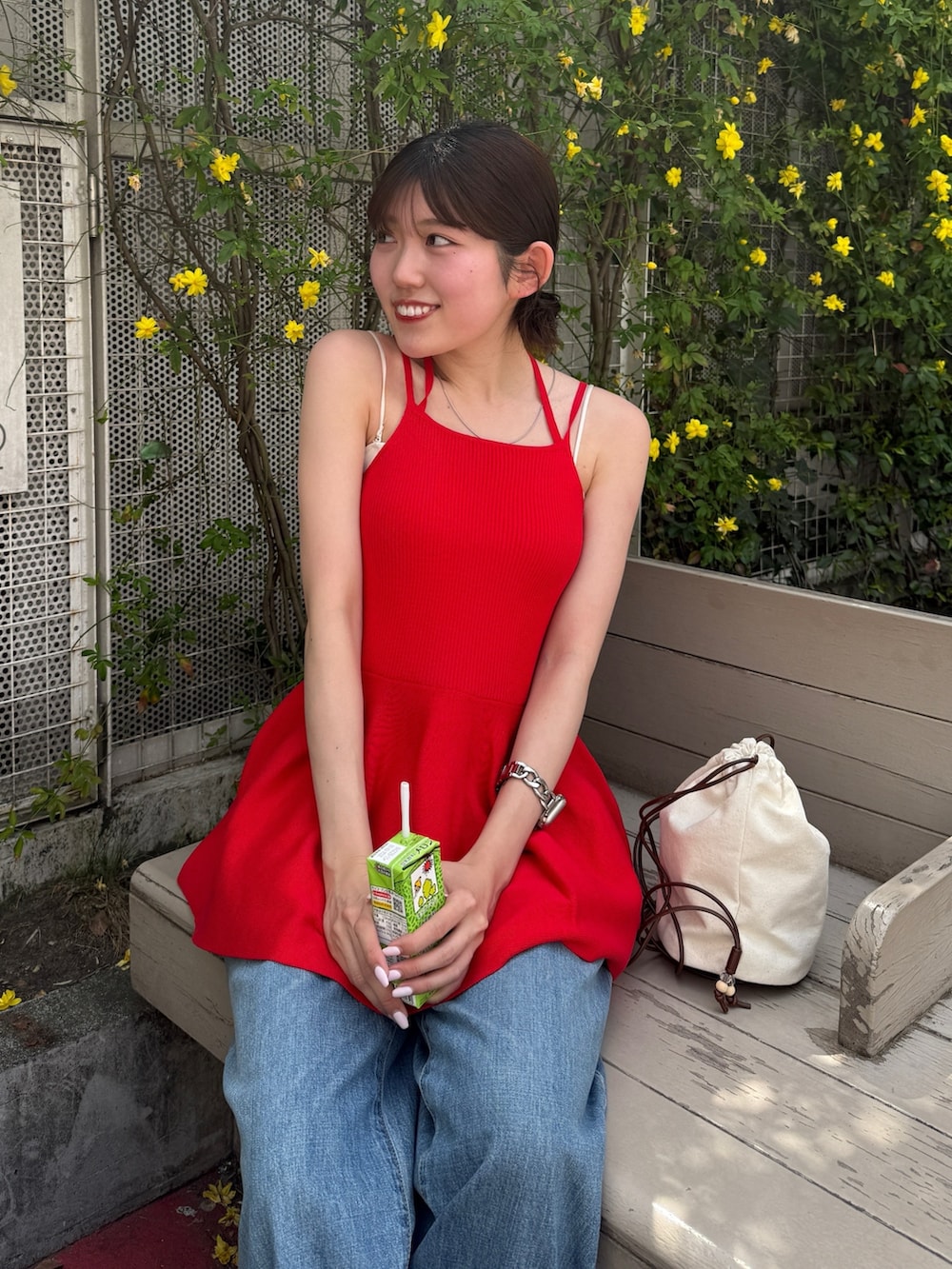 レッド系のキャミソール、ブルー系のデニムパンツ、ブラック系のブーツを着用したレディースの春コーディネートの4枚目の写真