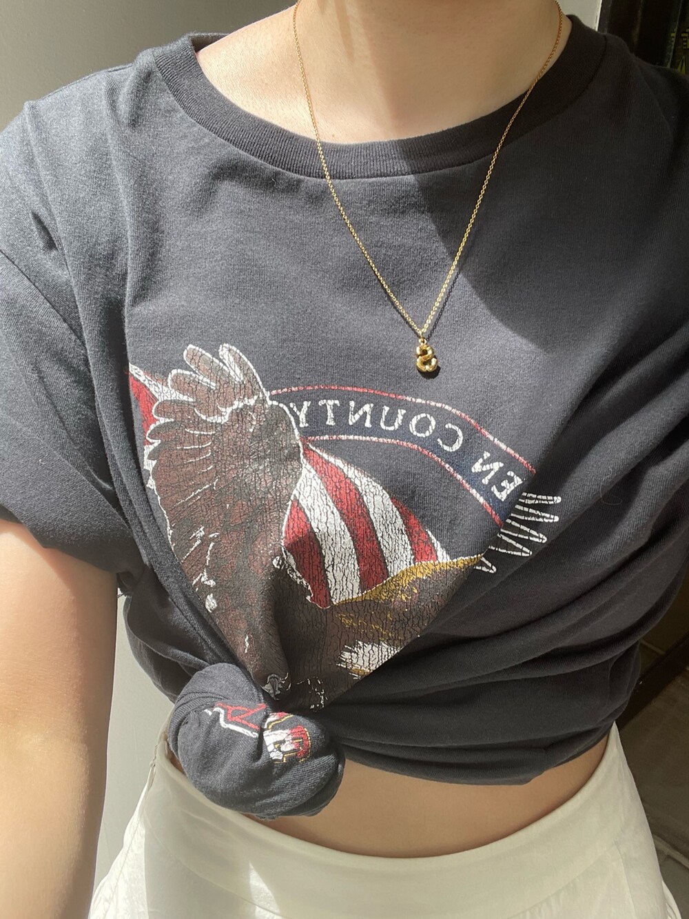 ホワイト系のスカート、グレー系のTシャツ/カットソー、ゴールド系のネックレスを着用したレディースの春コーディネートの7枚目の写真