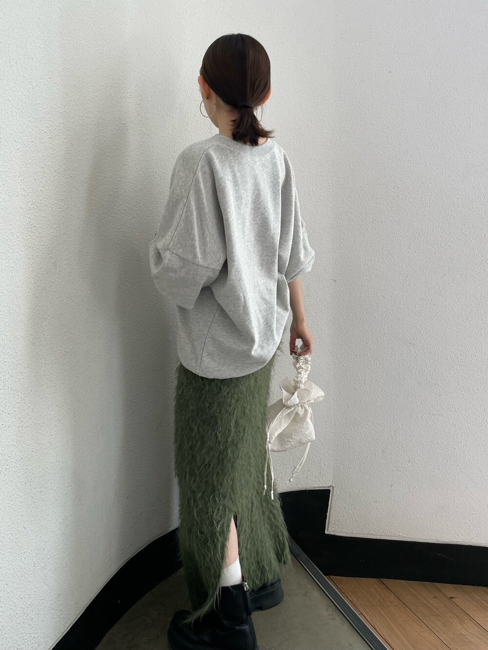 ホワイト系のハンドバッグ、ブラック系のブーツ、グレー系のスウェットを着用したレディースの秋コーディネートの4枚目の写真