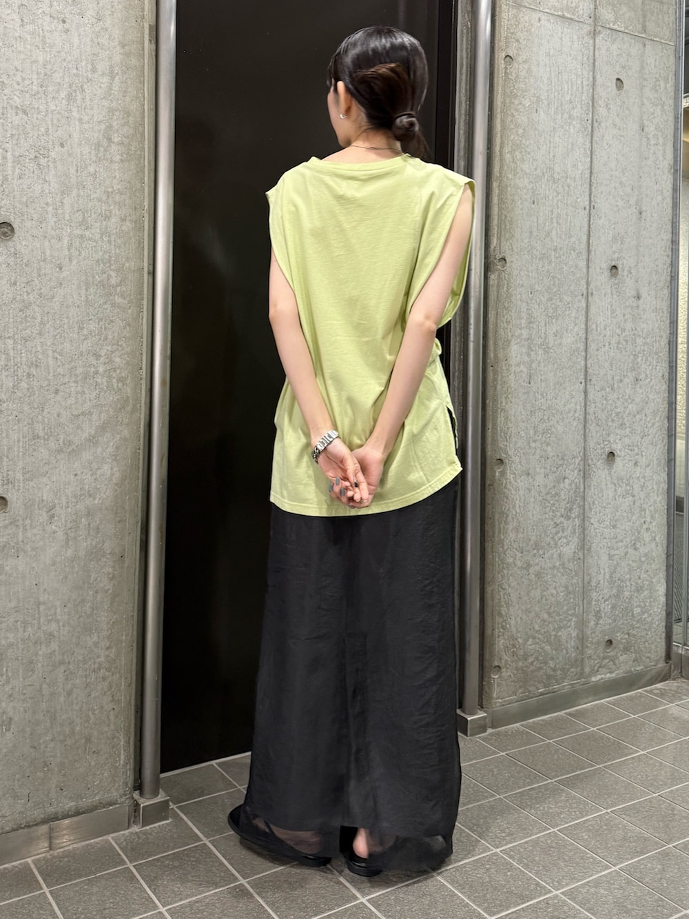 グレー系のスカート、グリーン系のタンクトップ、ブラック系のサンダルを着用したレディースの夏コーディネートの4枚目の写真