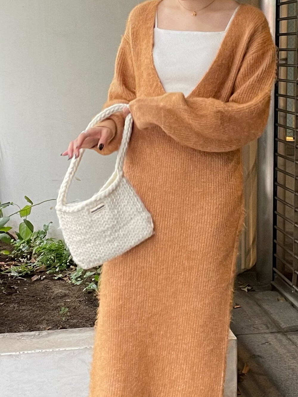 ホワイト系のハンドバッグ、オレンジ系のワンピースを着用したレディースの秋コーディネートの5枚目の写真