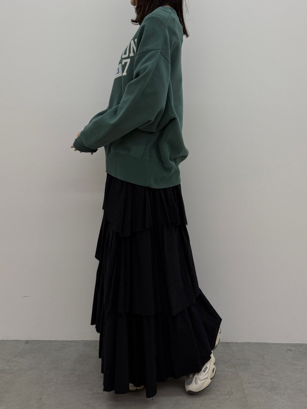 ブラック系のスカート、グリーン系のスウェットを着用したレディースの冬コーディネートの2枚目の写真