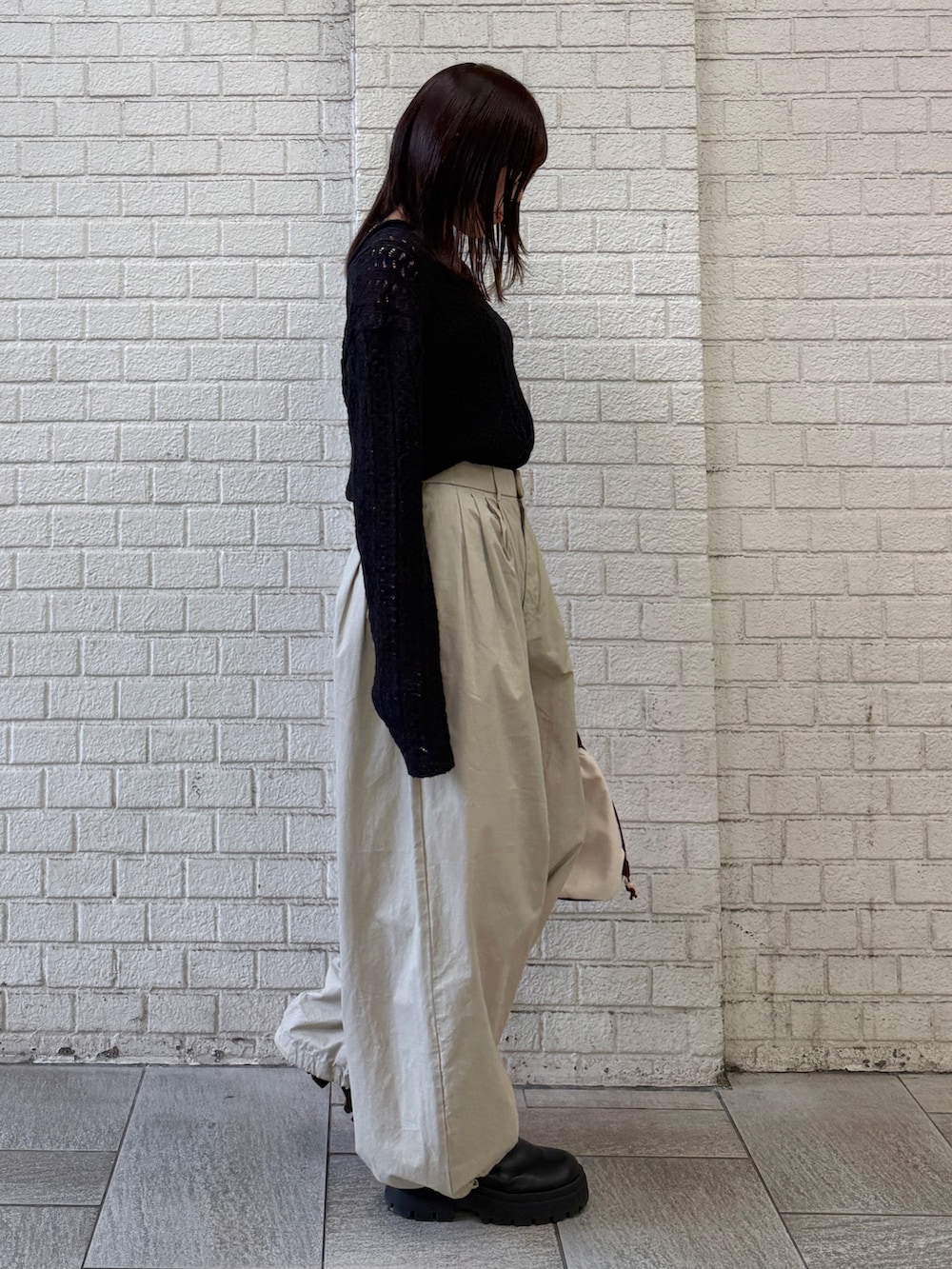 ベージュ系のその他パンツ、ホワイト系のショルダーバッグ、ブラック系のニット/セーターを着用したレディースの春コーディネートの3枚目の写真