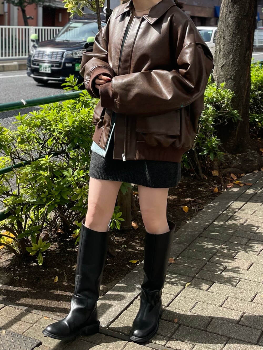 グレー系のスカート、ブラック系のブーツ、ブラウン系のブルゾンを着用したレディースの秋コーディネートの4枚目の写真