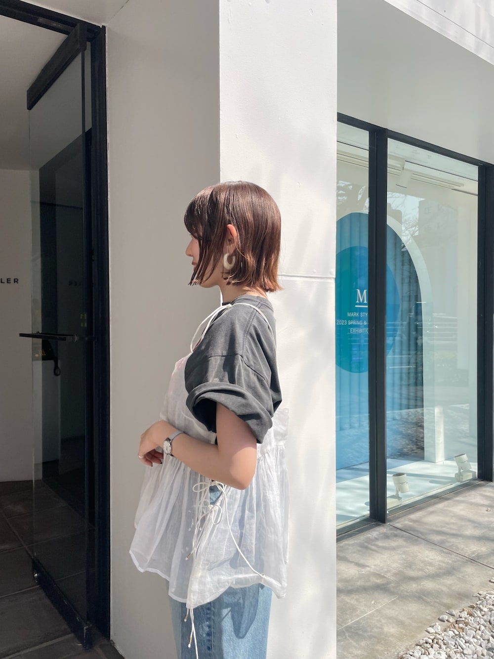 ブルー系のデニムパンツ、グレー系のTシャツ/カットソー、ホワイト系のショルダーバッグを着用したレディースの春コーディネートの6枚目の写真