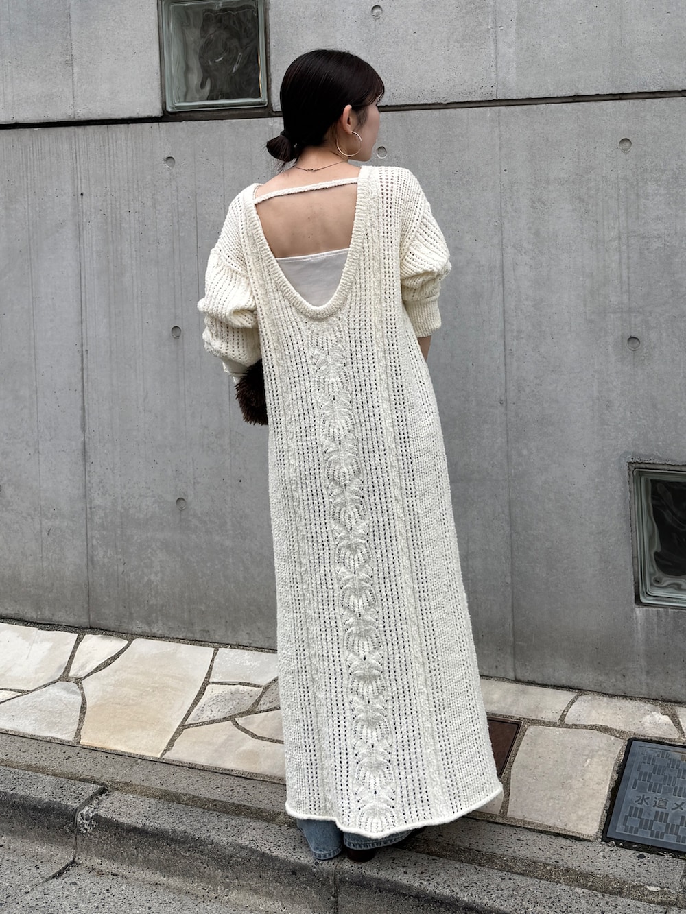 ホワイト系のワンピース、ブルー系のデニムパンツ、ブラウン系のブーツを着用したレディースの冬コーディネートの3枚目の写真