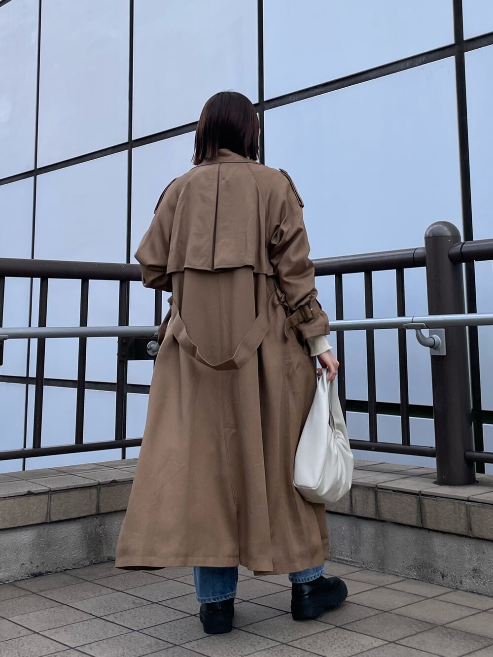 ホワイト系のハンドバッグ、ホワイト系のTシャツ/カットソー、ブルー系のデニムパンツを着用したレディースの冬コーディネートの7枚目の写真