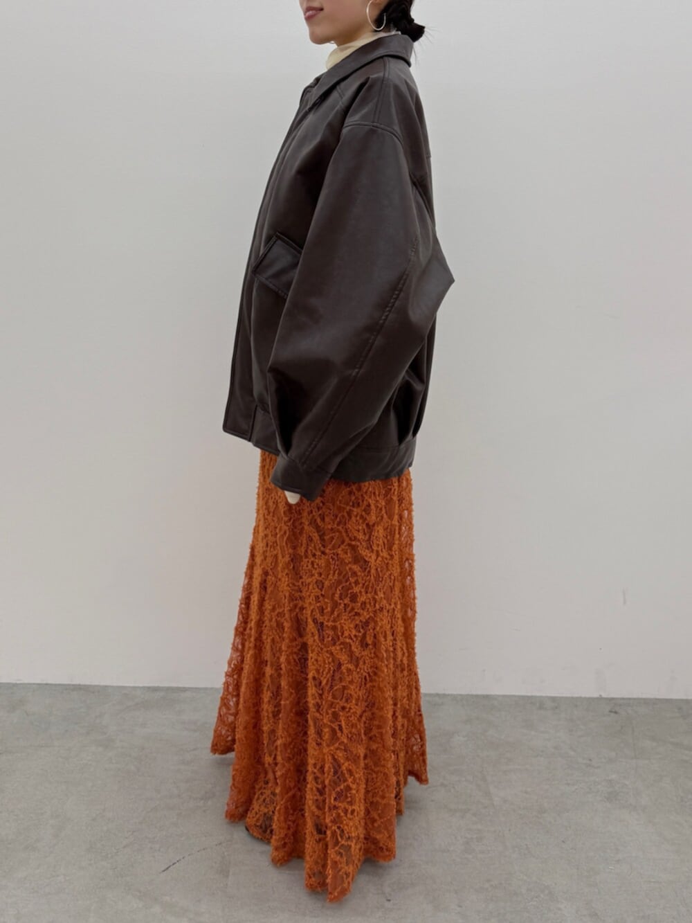 ブラック系のブーツ、ブラウン系のブルゾン、オレンジ系のスカートを着用したレディースの冬コーディネートの2枚目の写真