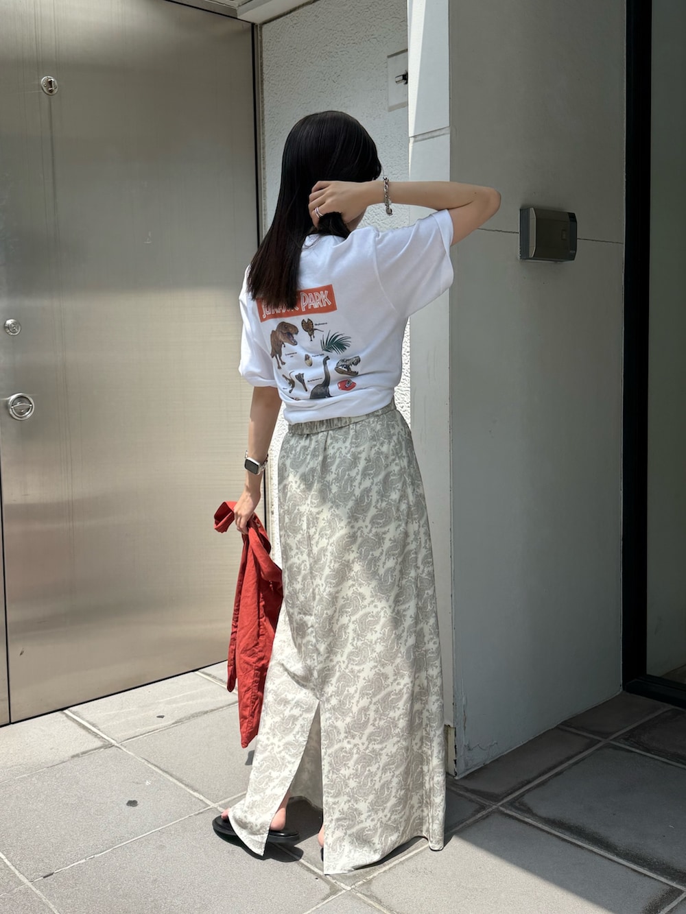 オレンジ系のトートバッグ、ホワイト系のTシャツ/カットソー、ブラック系のサンダルを着用したレディースの夏コーディネートの4枚目の写真