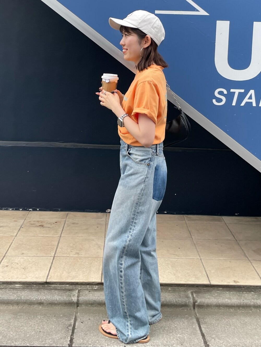 ブラック系のサンダル、ブルー系のデニムパンツ、オレンジ系のTシャツ/カットソーを着用したレディースの夏コーディネートの7枚目の写真