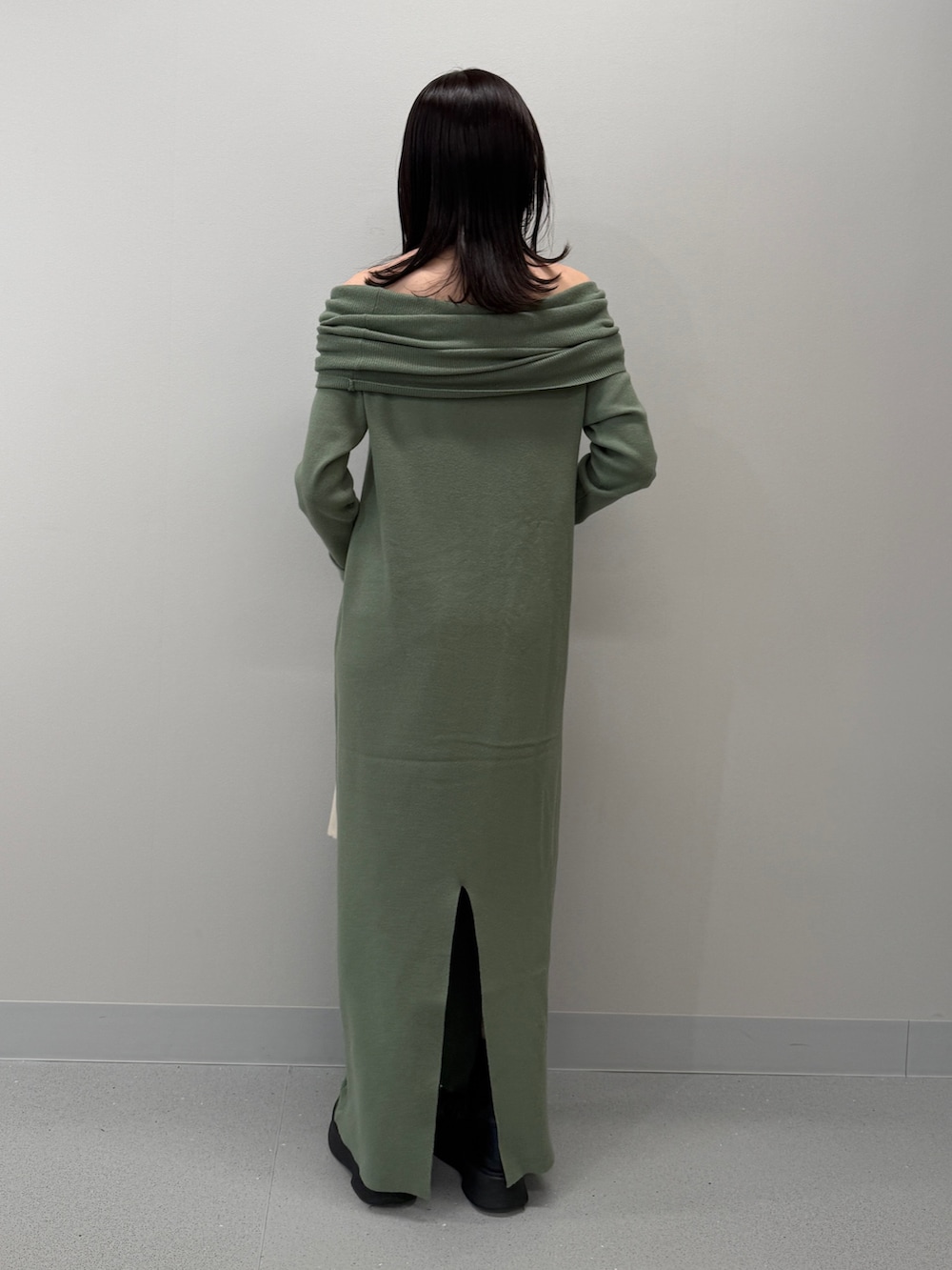 ホワイト系のトートバッグ、ブラック系のブーツ、グリーン系のワンピースを着用したレディースの冬コーディネートの3枚目の写真