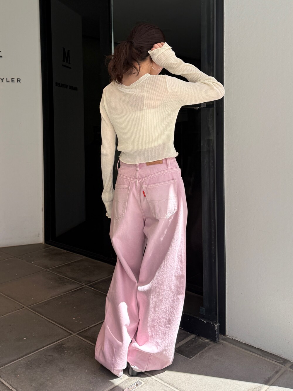 ピンク系のデニムパンツ、ブラック系のサンダル、ホワイト系のカーディガン/ボレロを着用したレディースの春コーディネートの3枚目の写真