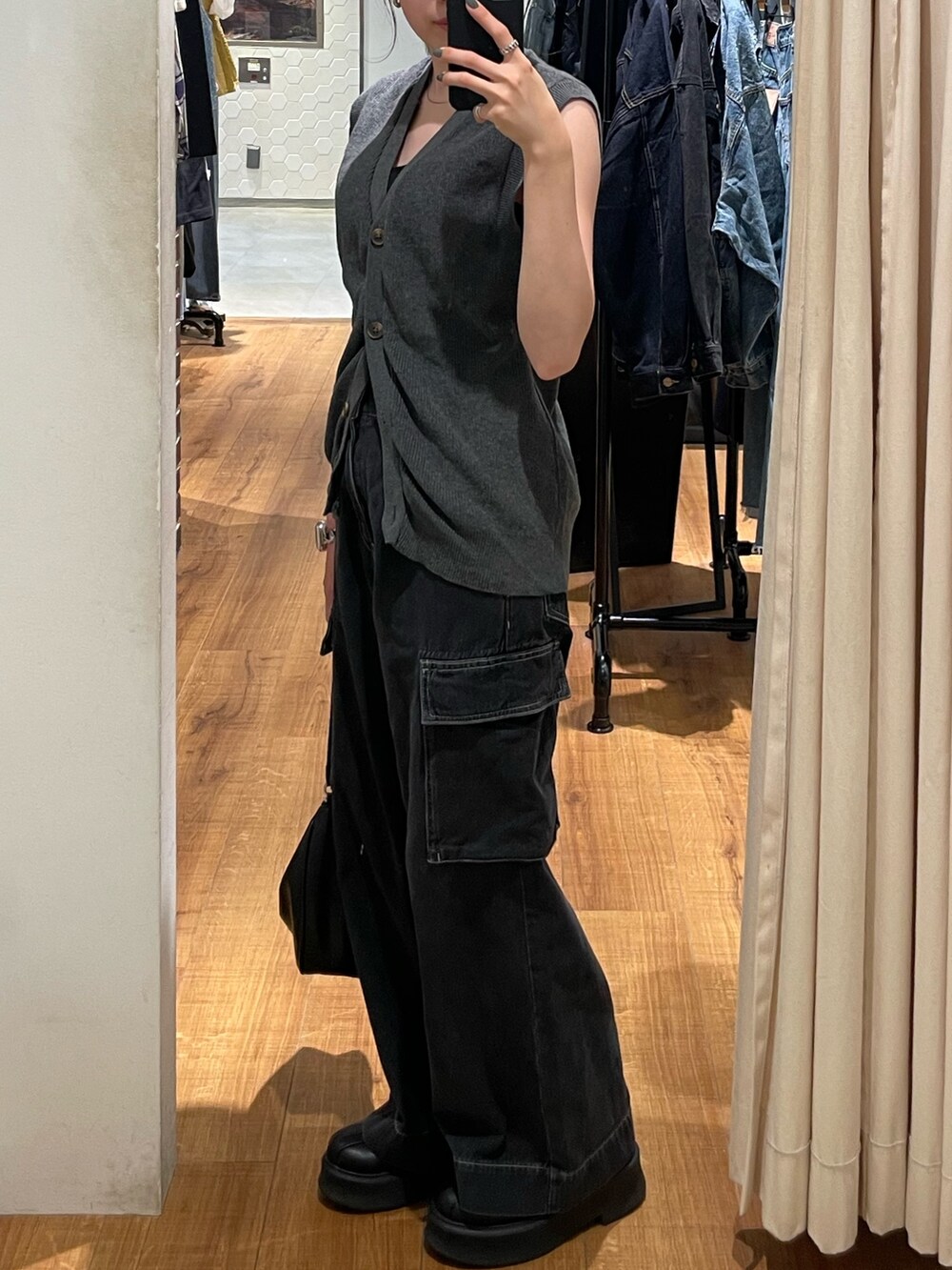 グレー系のベスト、ブラック系のブーツ、ブラック系のデニムパンツを着用したレディースの秋コーディネートの3枚目の写真