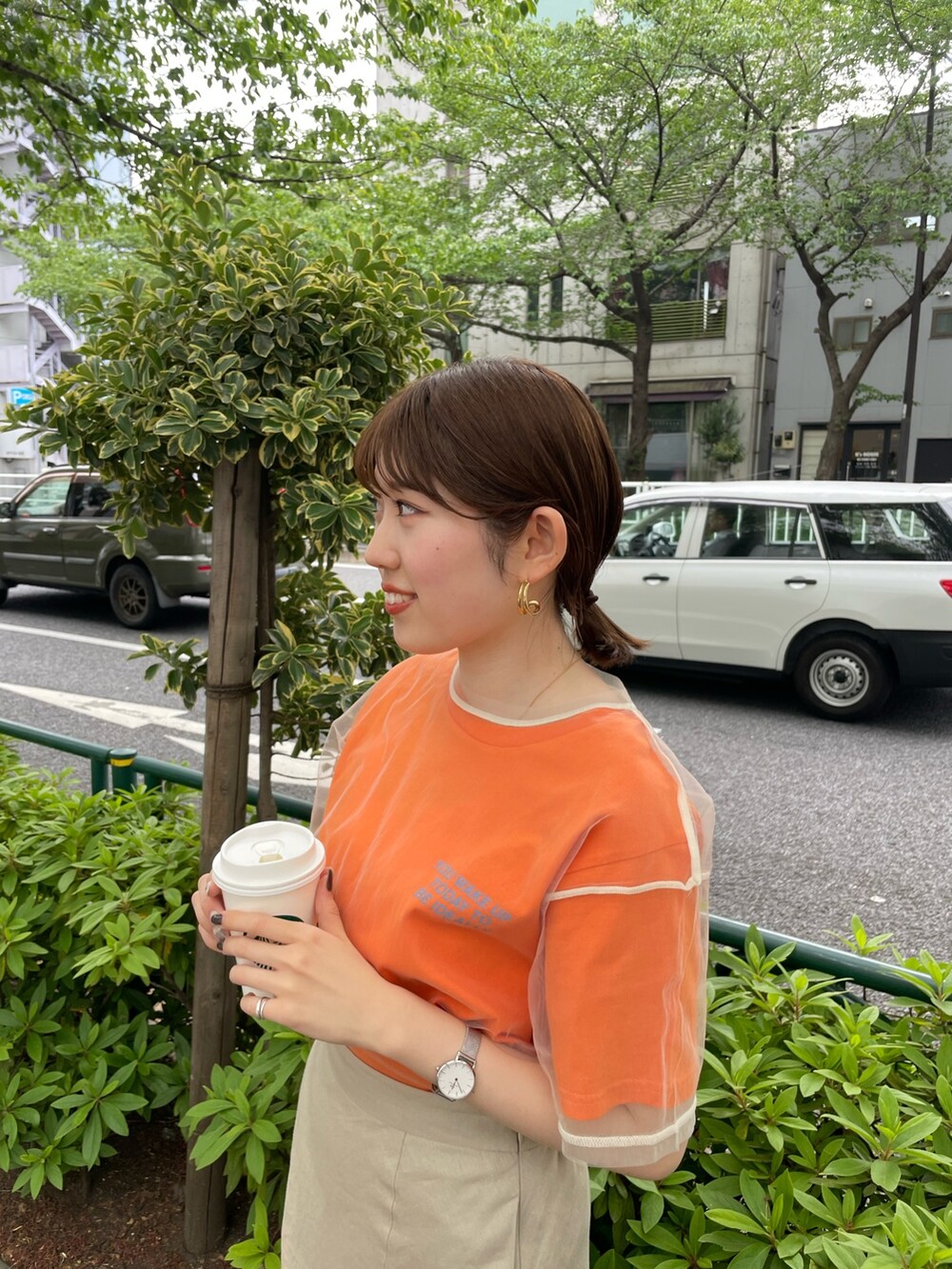 ホワイト系のサンダル、オレンジ系のTシャツ/カットソー、ベージュ系のスカートを着用したレディースの春コーディネートの5枚目の写真