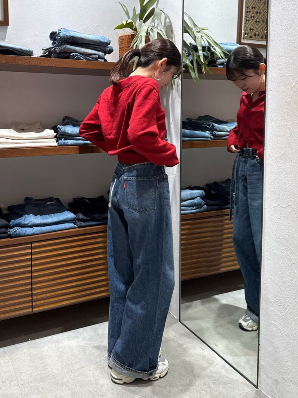 レッド系のカーディガン/ボレロ、ブルー系のデニムパンツを着用したレディースの秋コーディネートの6枚目の写真