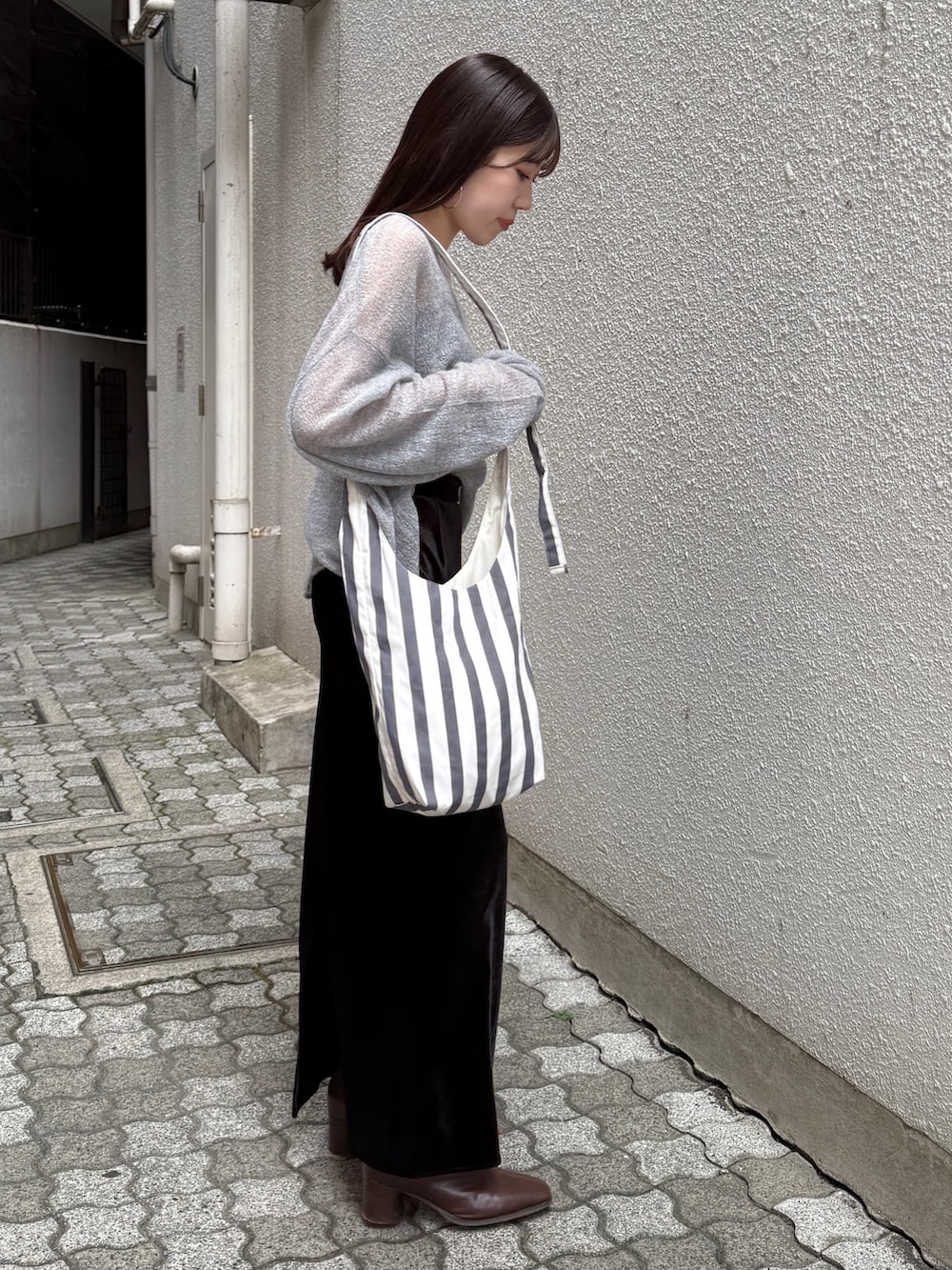 ブラック系のスカート、ブラウン系のブーツ、グレー系のニット/セーターを着用したレディースの秋コーディネートの7枚目の写真