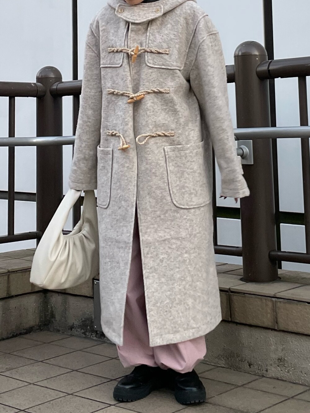 ピンク系のカーゴパンツ、ホワイト系のハンドバッグ、ホワイト系のダッフルコートを着用したレディースの冬コーディネートの7枚目の写真