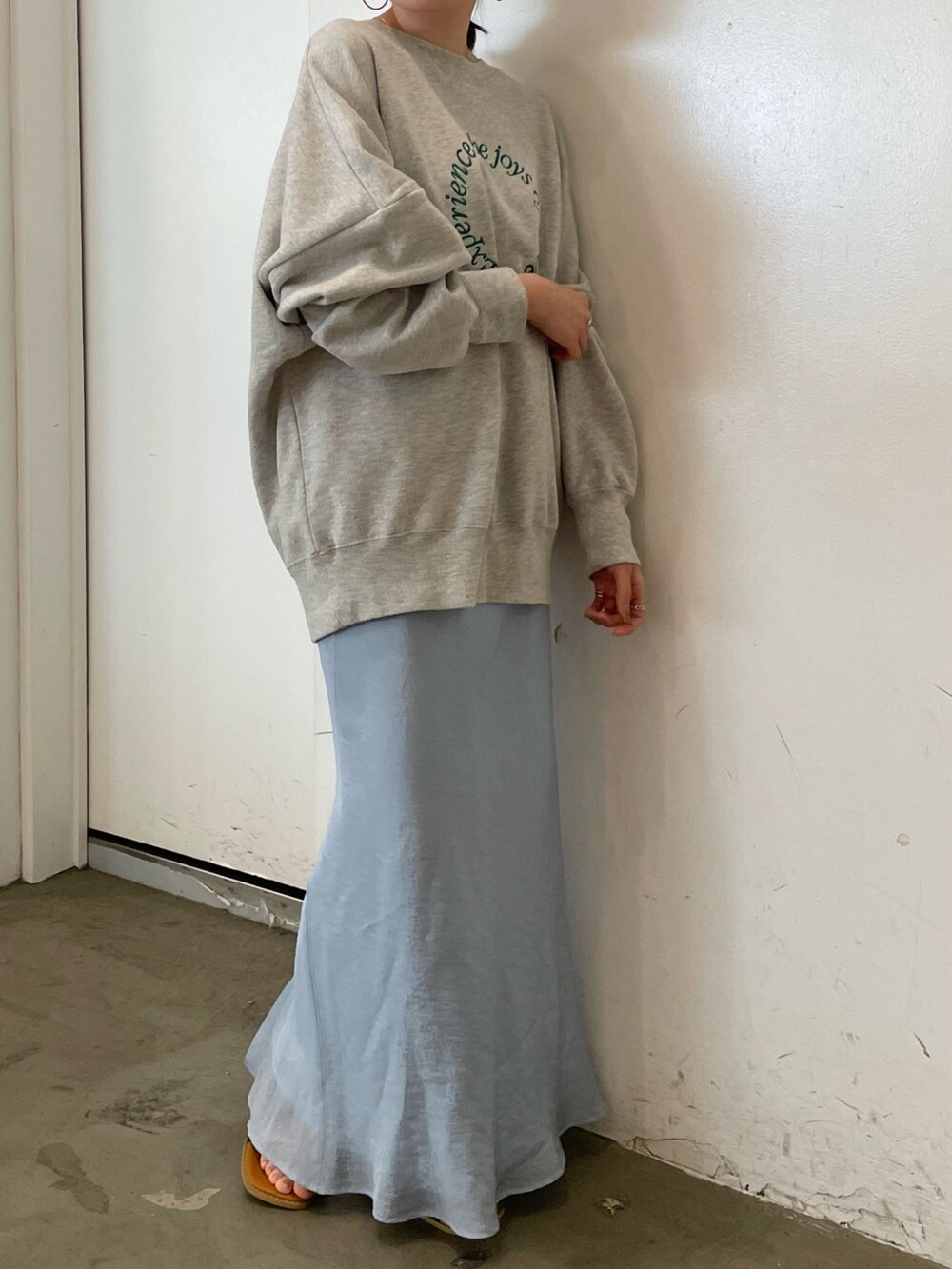 グレー系のスウェット、ブルー系のスカート、ブラック系のサンダルを着用したレディースの冬コーディネートの3枚目の写真