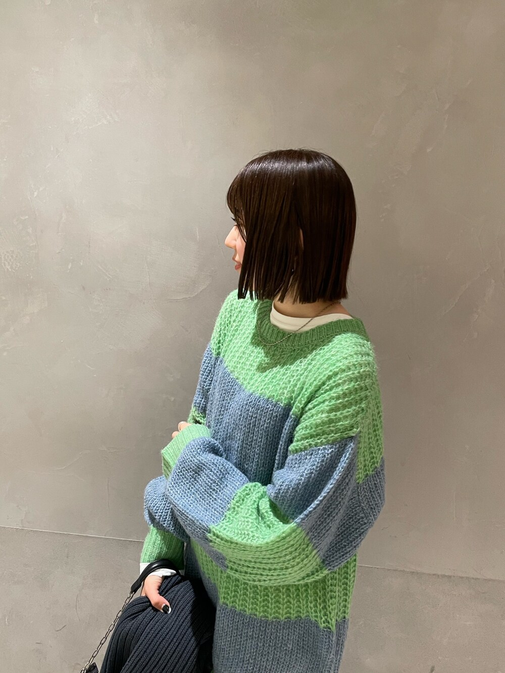 グリーン系のニット/セーター、ホワイト系のTシャツ/カットソー、グレー系のマフラーを着用したレディースの冬コーディネートの4枚目の写真