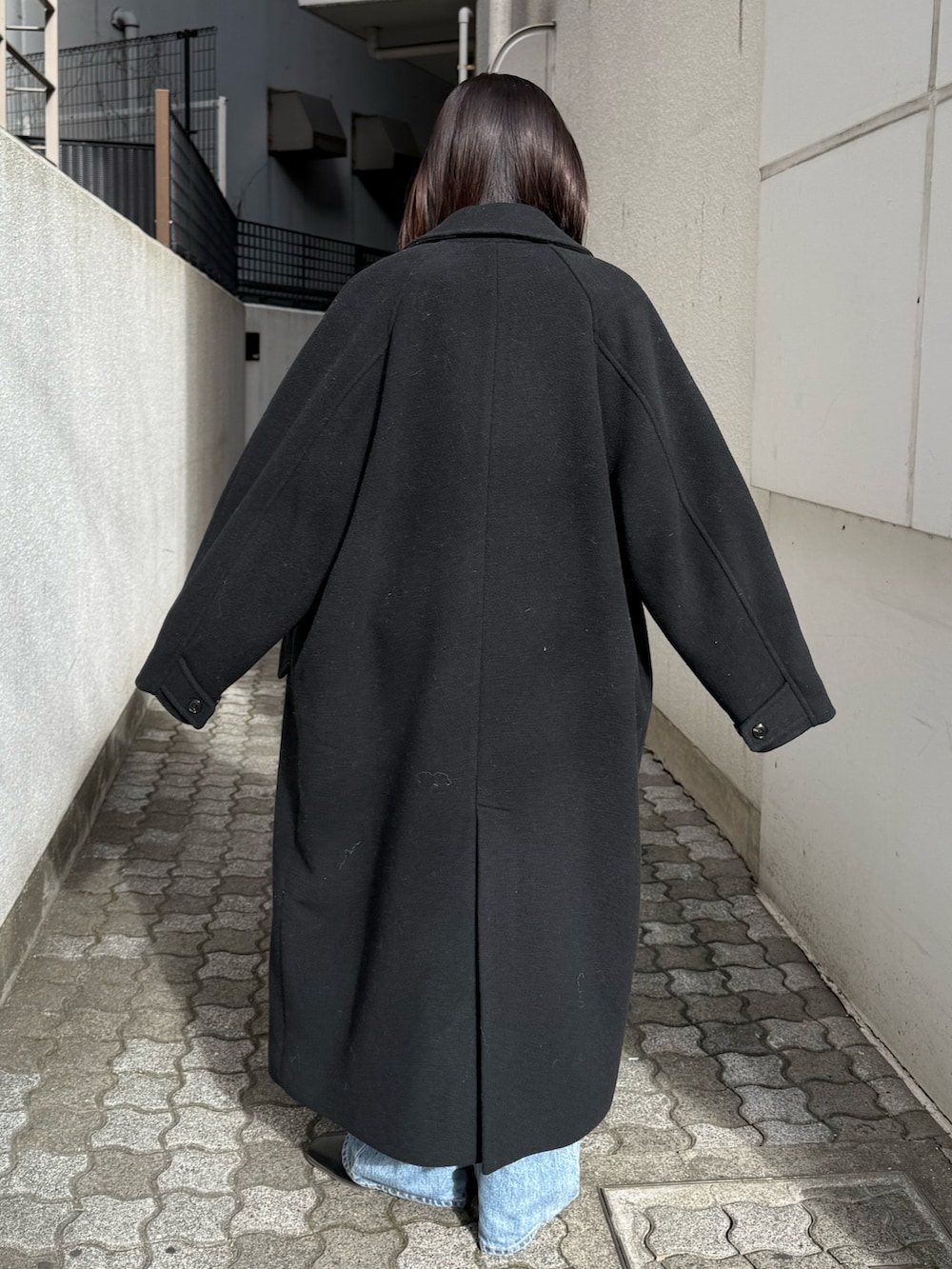 ブルー系のデニムパンツ、ブラック系のブーツ、ブラック系のチェスターコートを着用したレディースの冬コーディネートの4枚目の写真