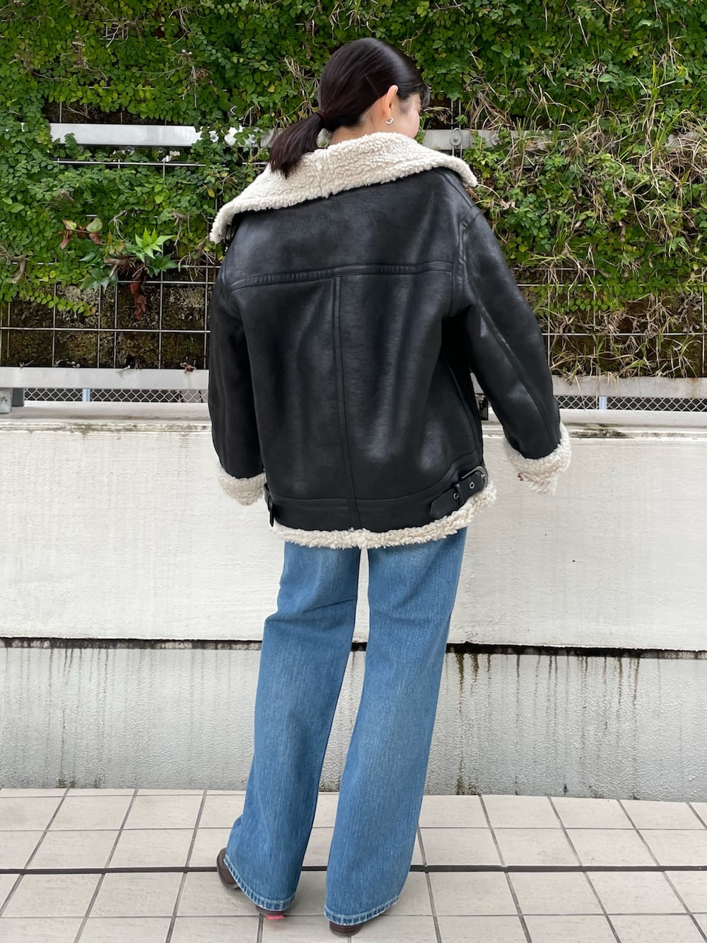 ブルー系のデニムパンツ、ブラウン系のブーツ、ホワイト系のニット/セーターを着用したレディースの秋コーディネートの4枚目の写真