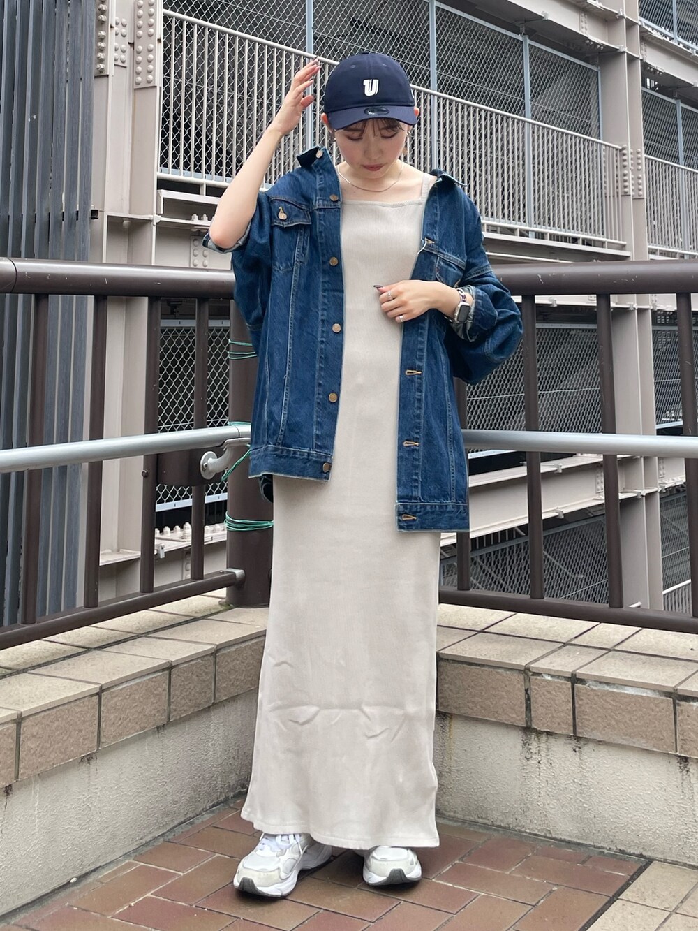 グレー系のワンピース、ブルー系のデニムジャケット、ブルー系のキャップを着用したレディースの夏コーディネートの2枚目の写真