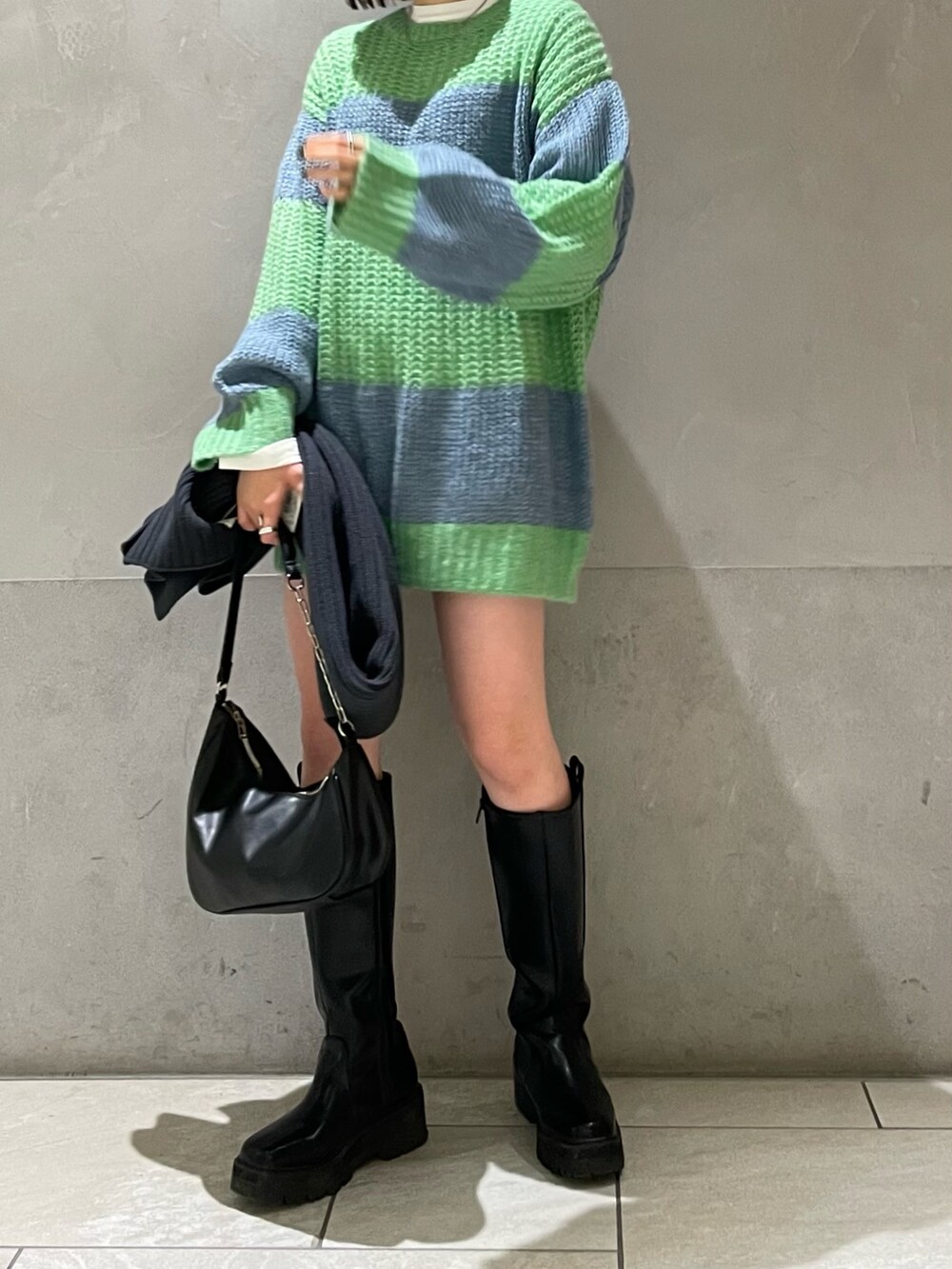 グリーン系のニット/セーター、ホワイト系のTシャツ/カットソー、グレー系のマフラーを着用したレディースの冬コーディネートの3枚目の写真