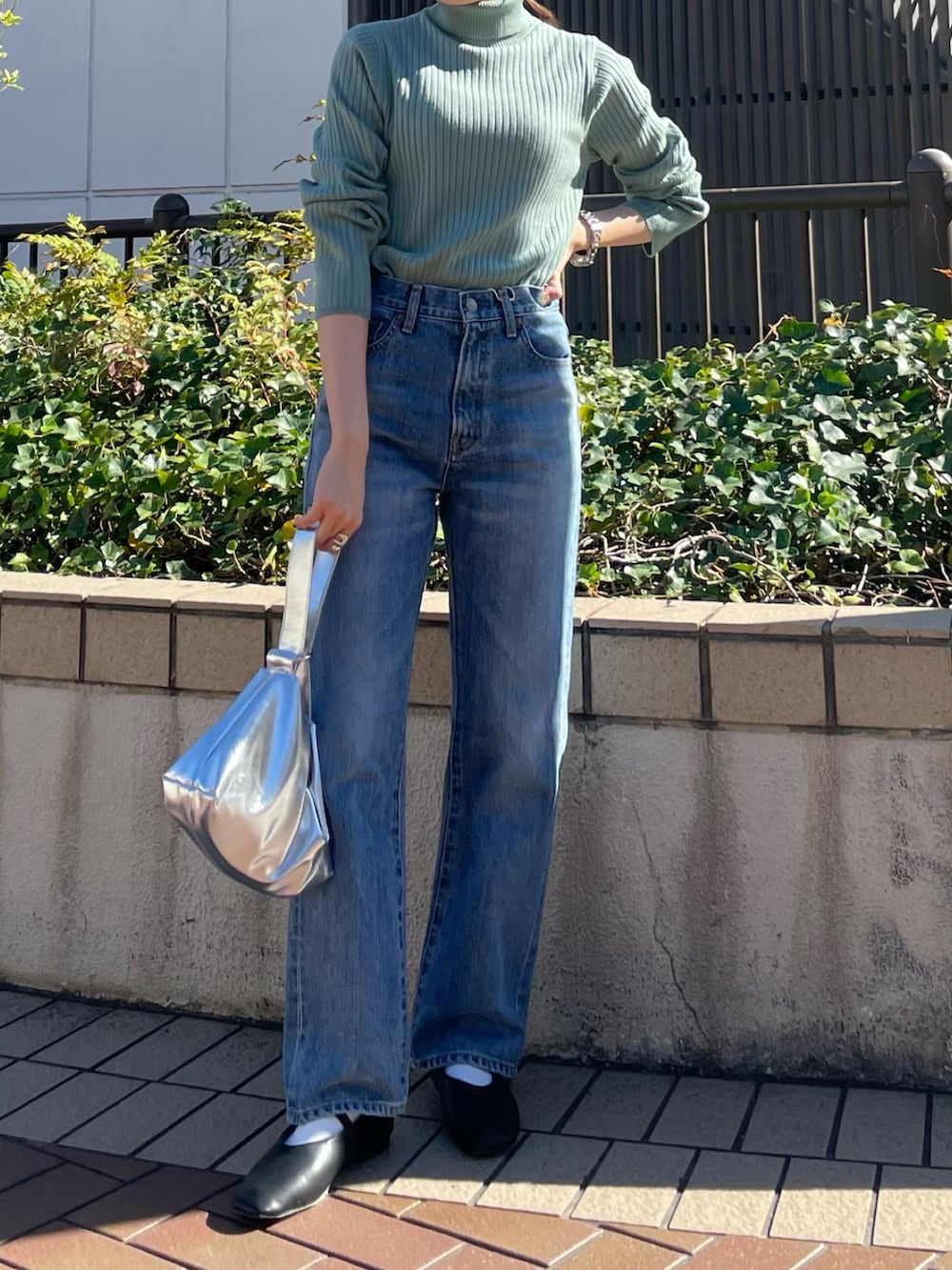 ブラウン系のブルゾン、ブラック系のパンプス、ブルー系のデニムパンツを着用したレディースの秋コーディネートの4枚目の写真