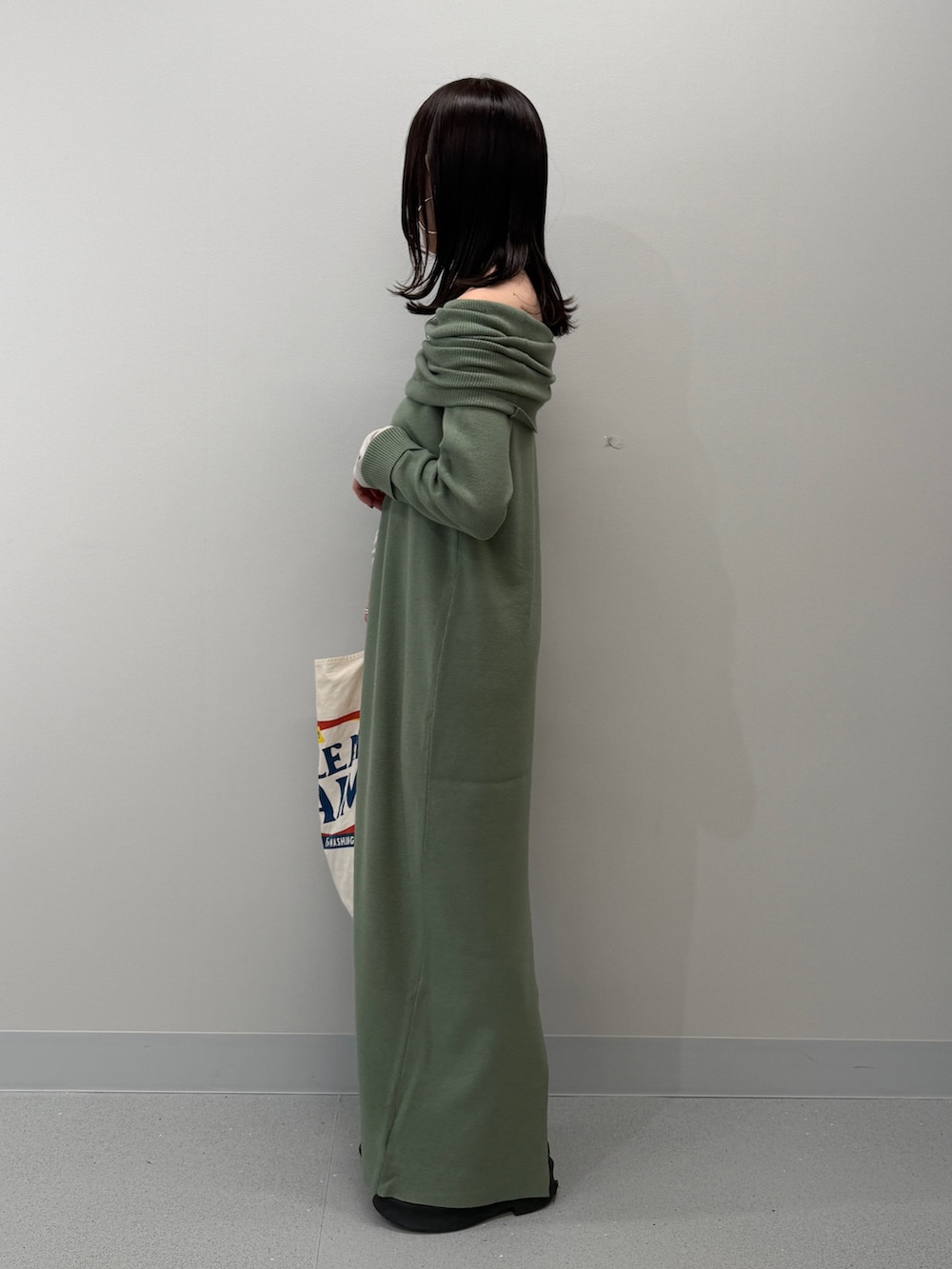 ホワイト系のトートバッグ、ブラック系のブーツ、グリーン系のワンピースを着用したレディースの冬コーディネートの2枚目の写真