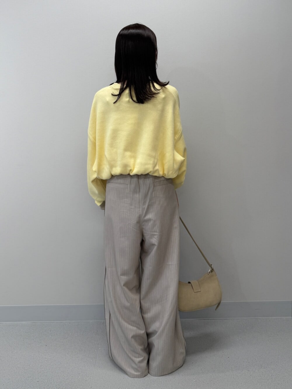 ベージュ系のハンドバッグ、イエロー系のニット/セーター、ブラック系のブーツを着用したレディースの冬コーディネートの5枚目の写真