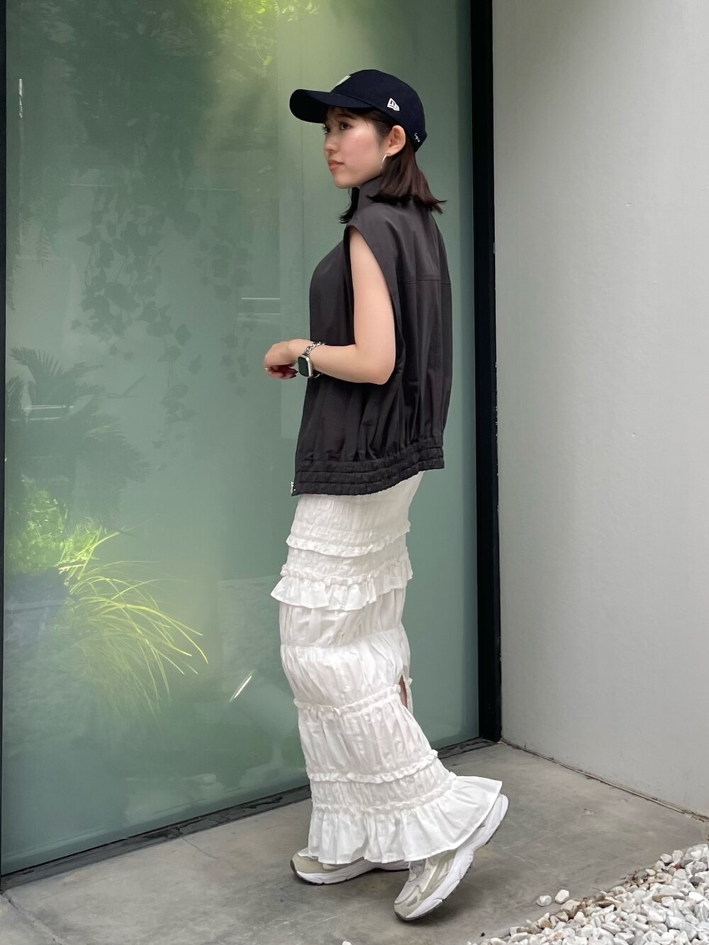 グレー系のベスト、ホワイト系のスカート、ブルー系のキャップを着用したレディースの夏コーディネートの4枚目の写真