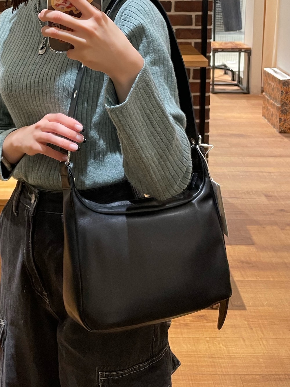グリーン系のニット/セーター、ブラック系のショルダーバッグ、ブラック系のデニムパンツを着用したレディースの冬コーディネートの7枚目の写真