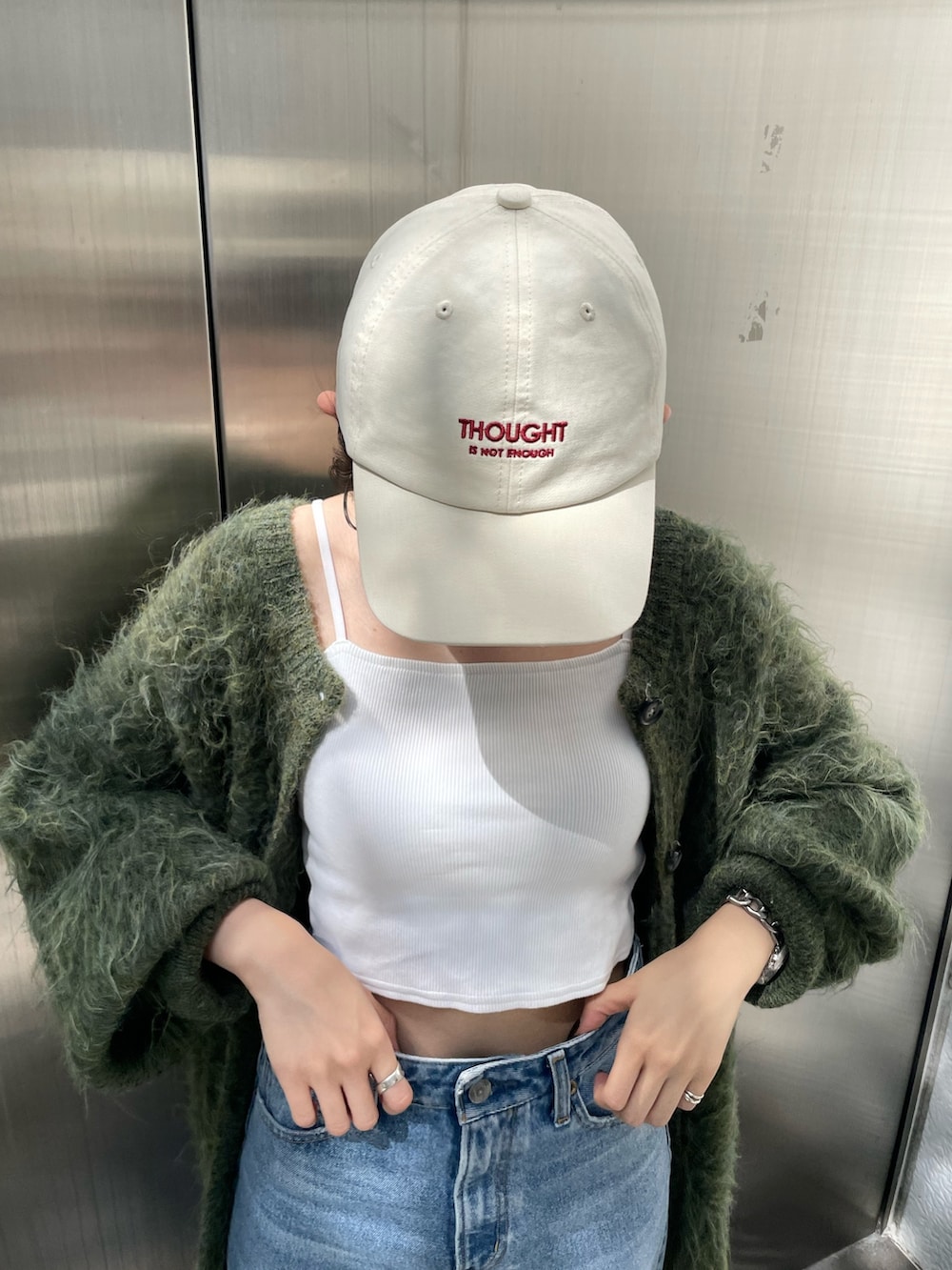 グリーン系のカーディガン/ボレロ、ベージュ系のブーツ、ブルー系のデニムパンツを着用したレディースの秋コーディネートの6枚目の写真