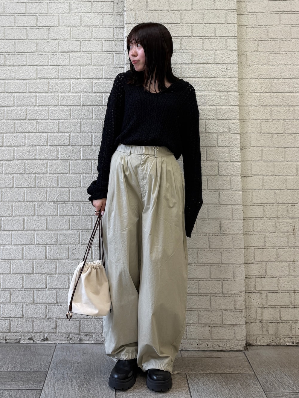 ベージュ系のその他パンツ、ホワイト系のショルダーバッグ、ブラック系のニット/セーターを着用したレディースの春コーディネートの4枚目の写真